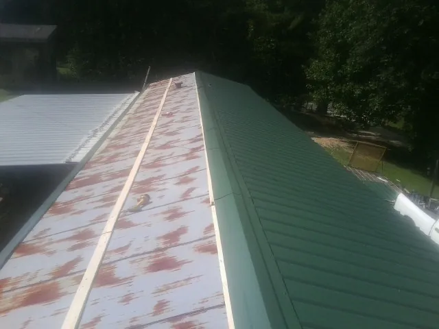 Old rusted panels beside newly installed green metal roofing — Wind Damage Roof Repair by Roofing Brothers in Plymouth Meeting