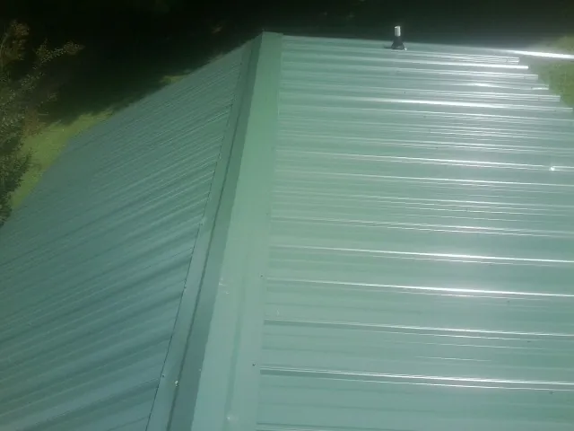 New green metal panels meeting at the ridge of a roof — Flat Roof Repair work by our crew in Plymouth Meeting