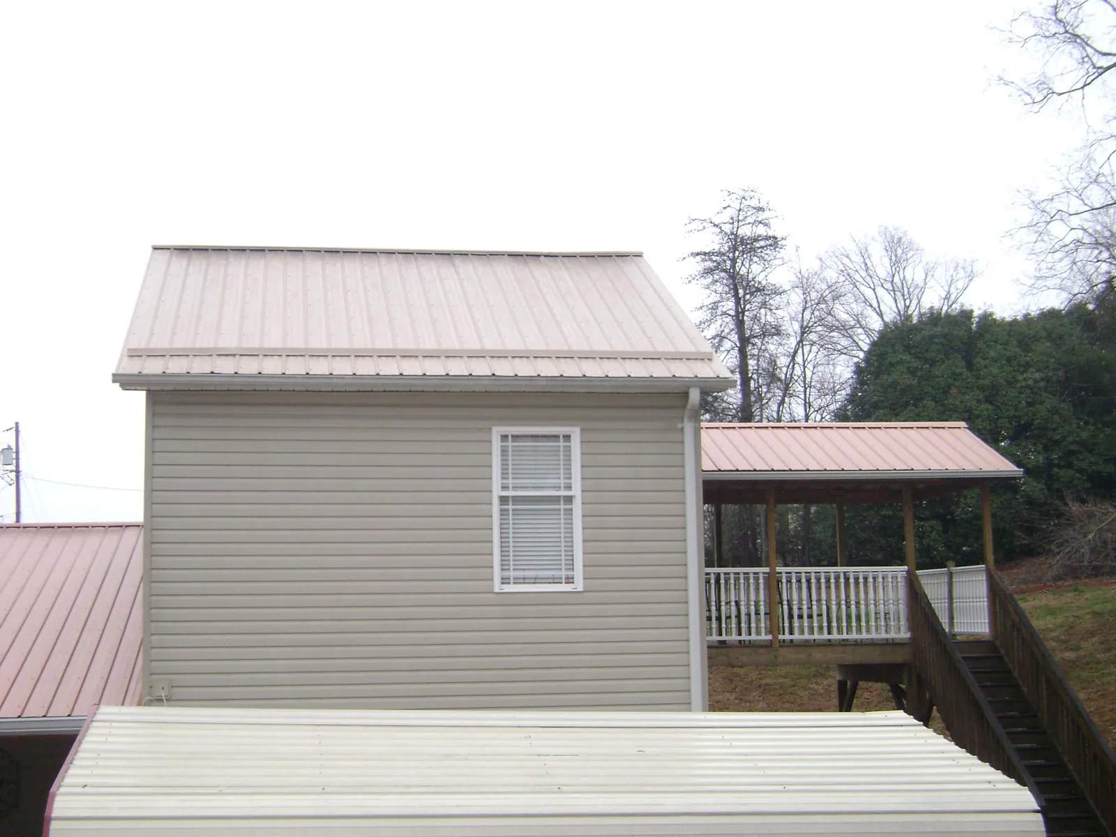 Tan metal roofs on a two story addition and attached porch, from a Roof Replacement job in Plymouth Meeting