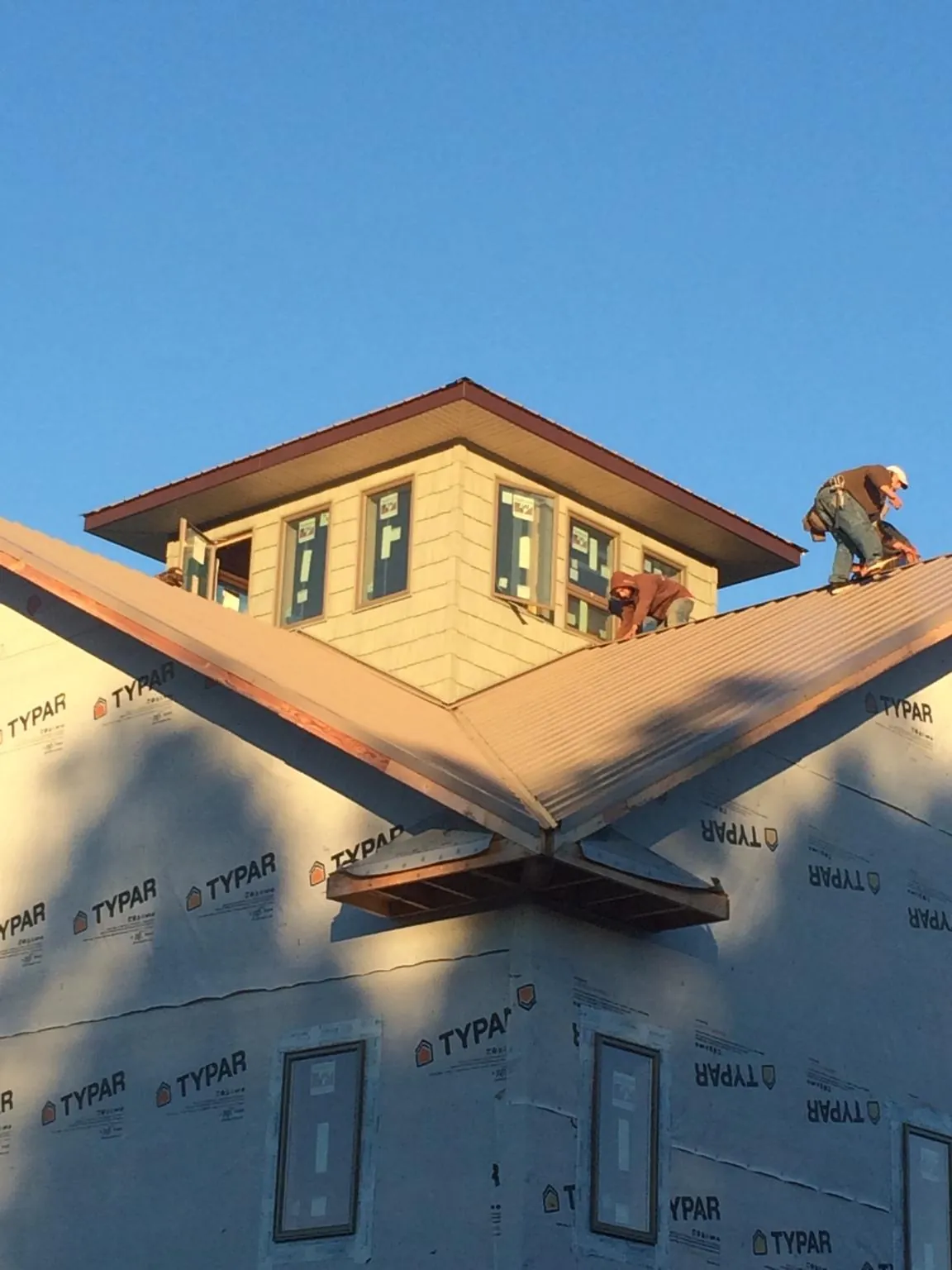 Roofers working around a rooftop cupola on a new metal roof at sunset — Roof Waterproofing in Plymouth Meeting by Roofing Brothers